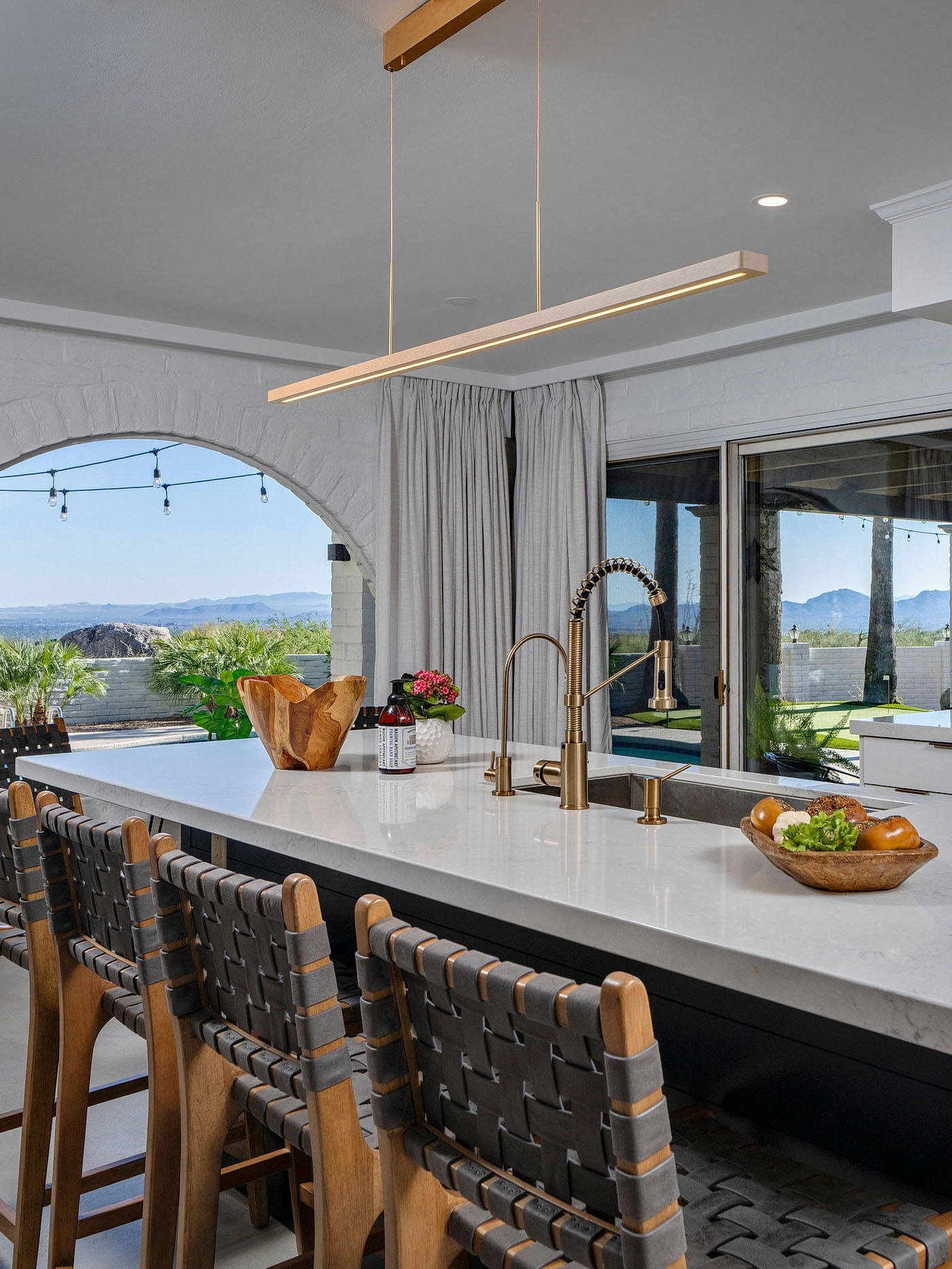 Bright remodeled kitchen featuring a large quartz island, custom cabinetry, designer lighting, bar seating, and expansive views of the Tucson desert landscape