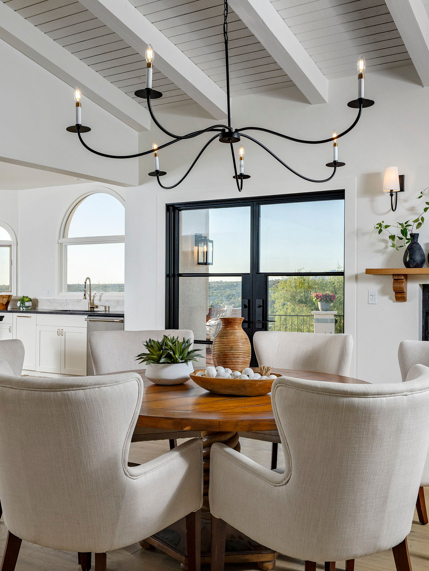 Bright dining space featuring vaulted ceilings, fireplace, large glass doors, and direct access to an expansive outdoor entertaining patio