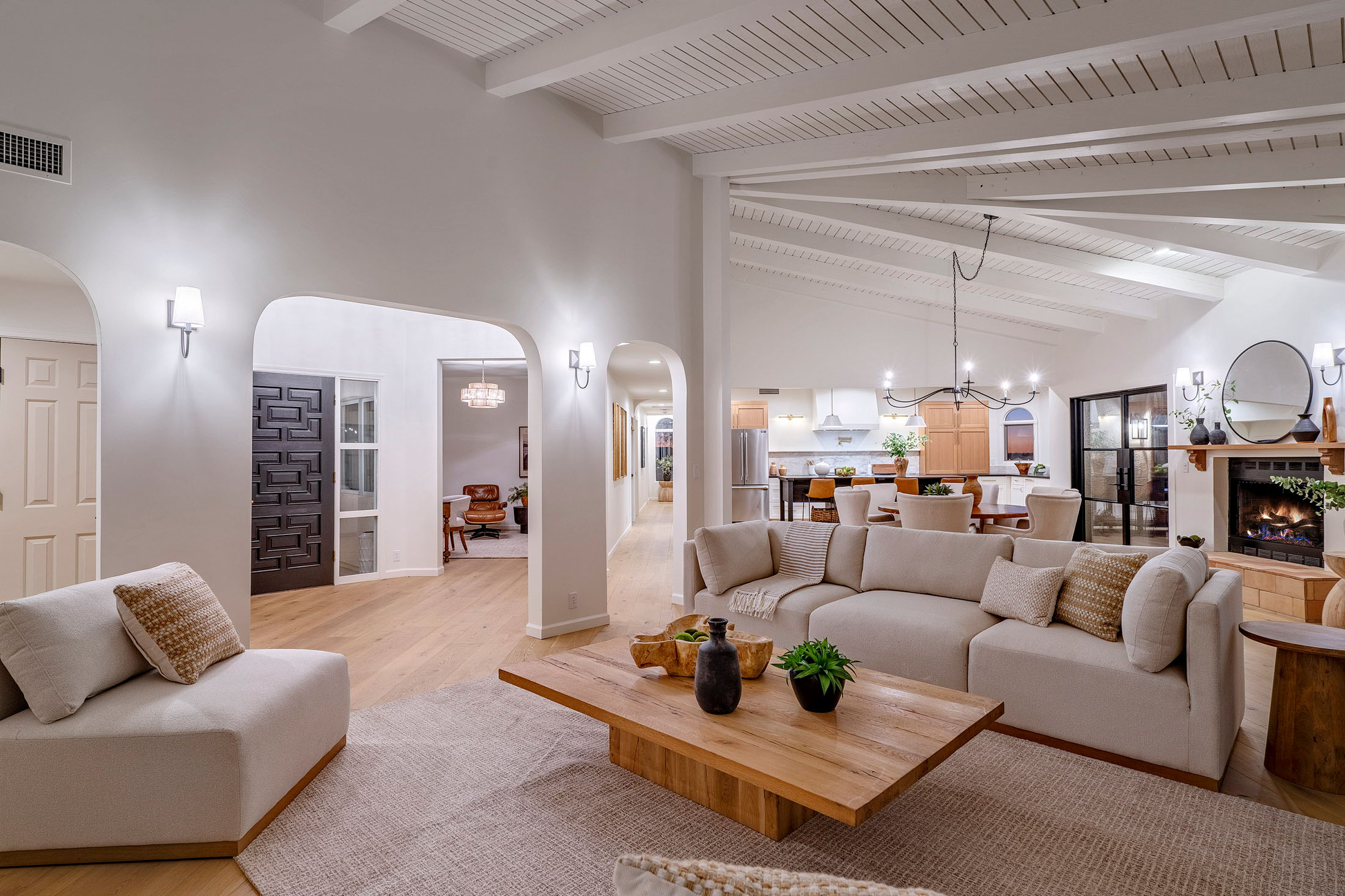 Light-filled living room renovation with vaulted ceilings, custom fireplace, white oak floors, and seamless connection to gathering spaces