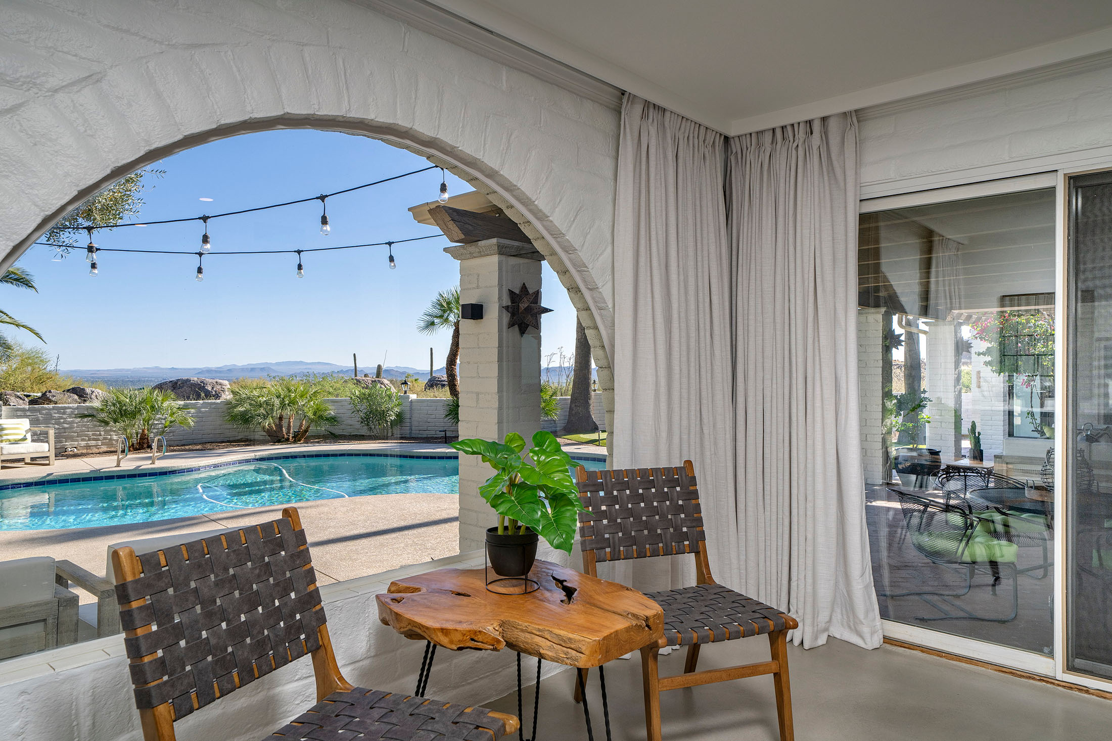 Bright sitting area overlooking a private pool and Sonoran Desert mountain views with arched architecture, outdoor entertaining space, and resort style Tucson living