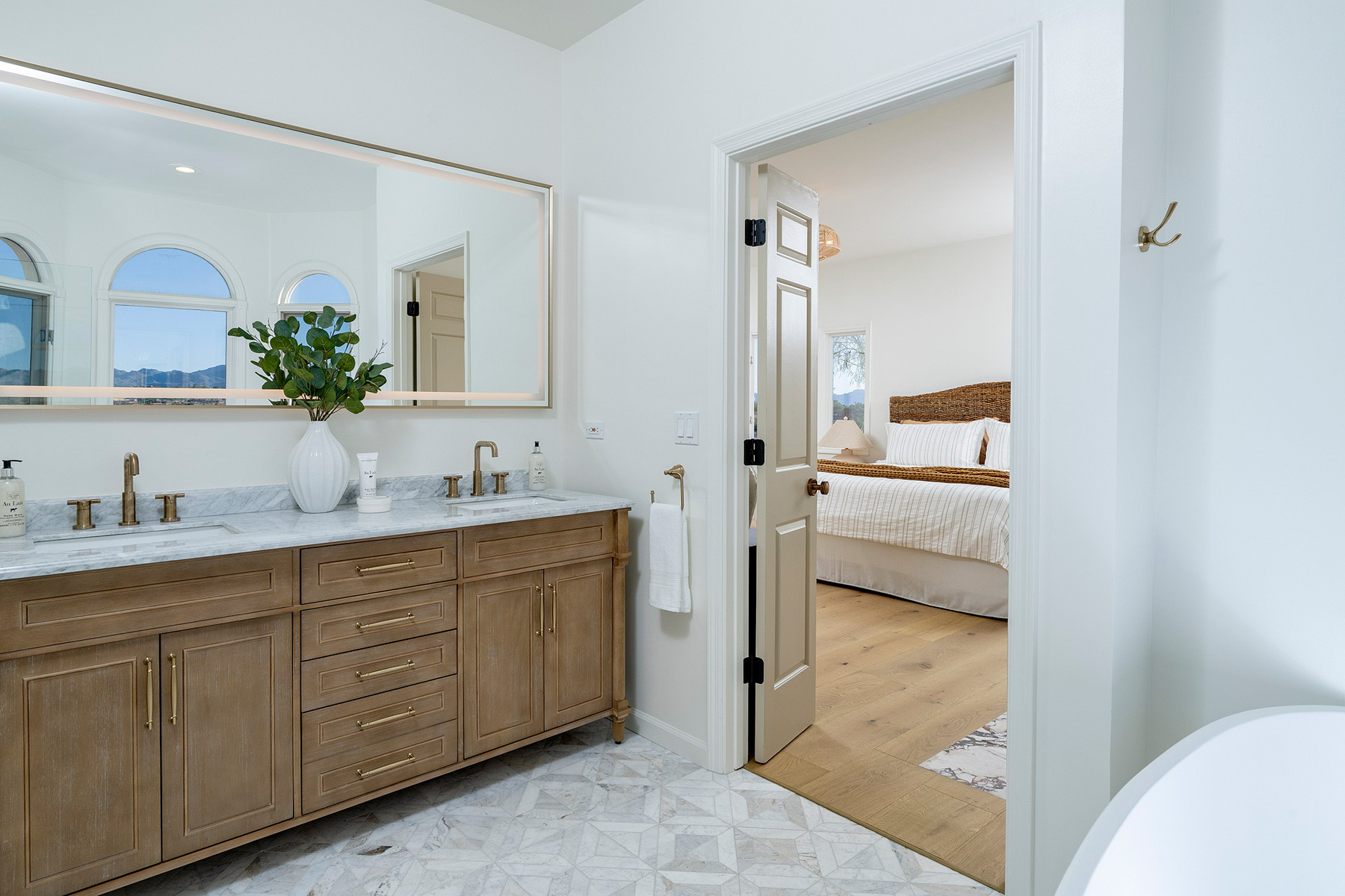 Elegant bathroom featuring custom wood vanity, marble countertops, brass fixtures, and timeless renovation craftsmanship