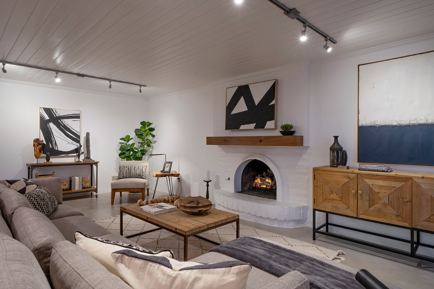 Updated Tucson living room featuring a white brick fireplace, polished concrete floors, custom lighting, modern furnishings, and open concept entertaining space