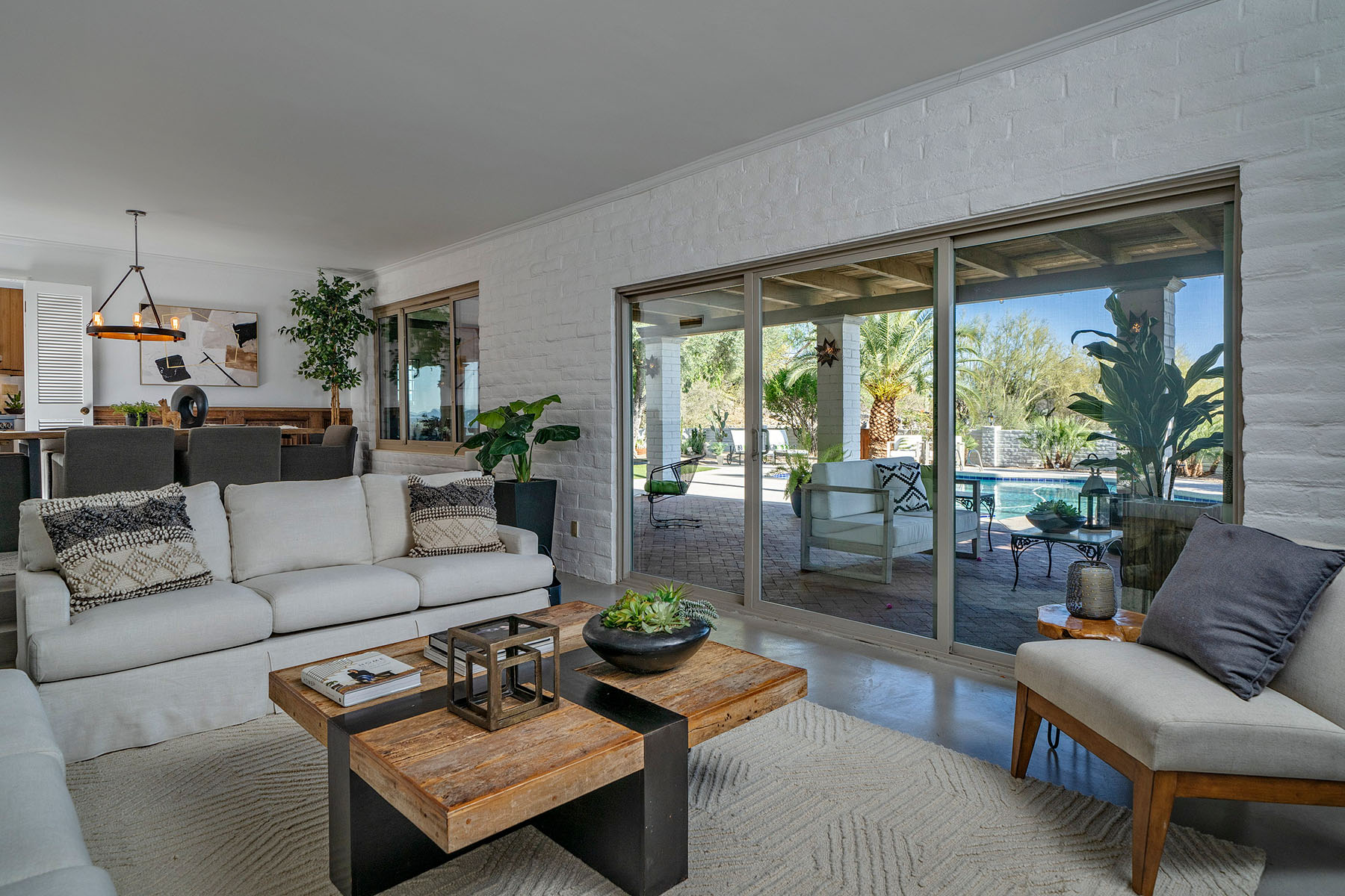 Open living room with large windows and sliding glass doors overlooking the backyard pool, showcasing indoor outdoor living and modern Southwest design