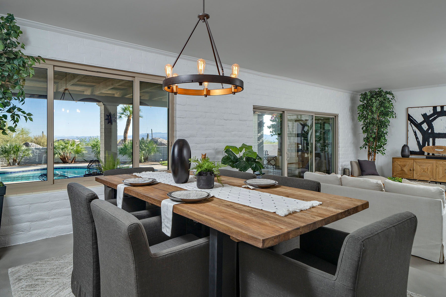 Formal dining area overlooking the backyard pool with large windows, custom lighting, open floor plan, and seamless connection to the living spaces