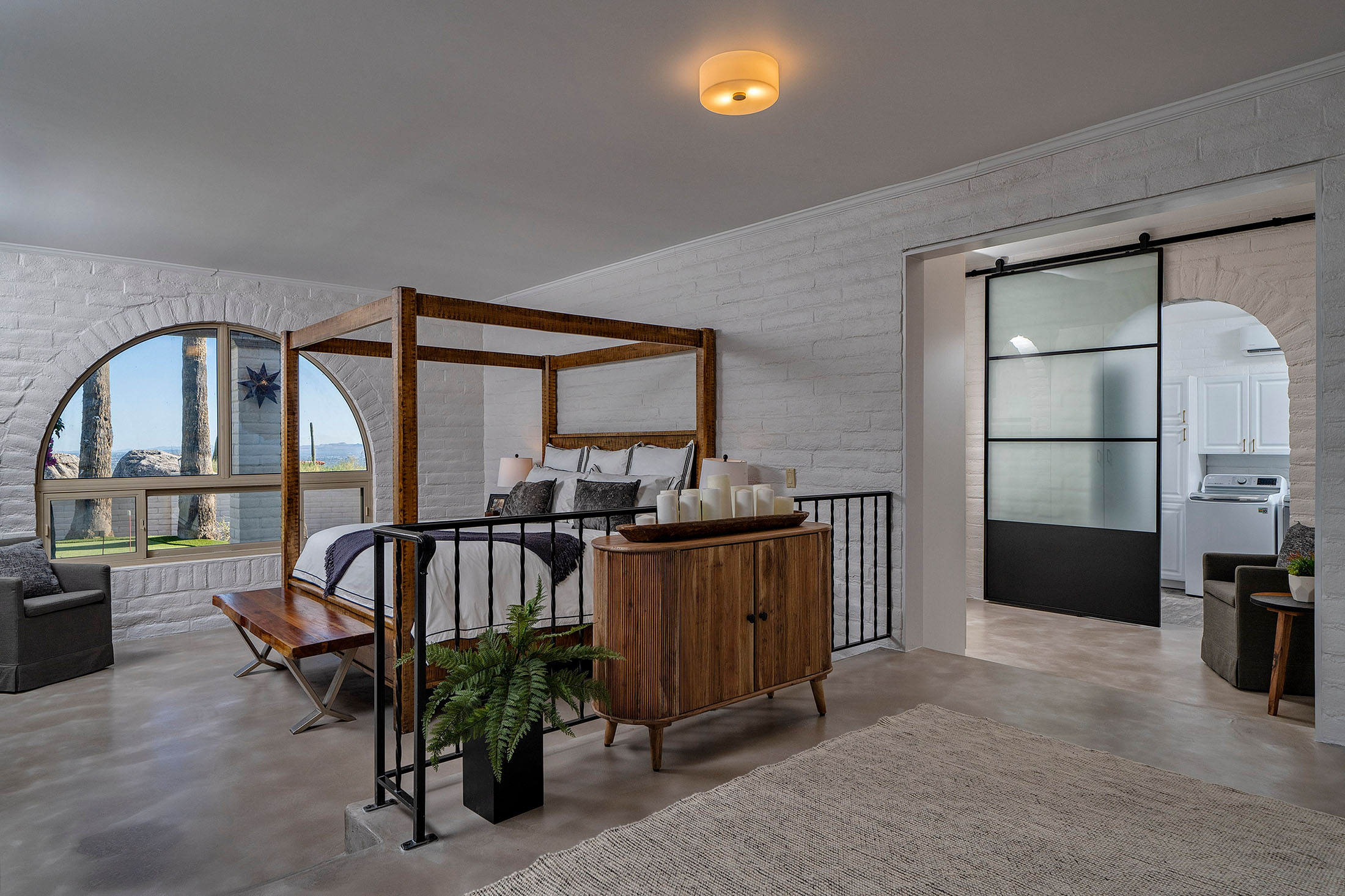 Elegant primary suite with arched windows, custom furnishings, polished concrete floors, and spacious layout creating a private retreat in Tucson